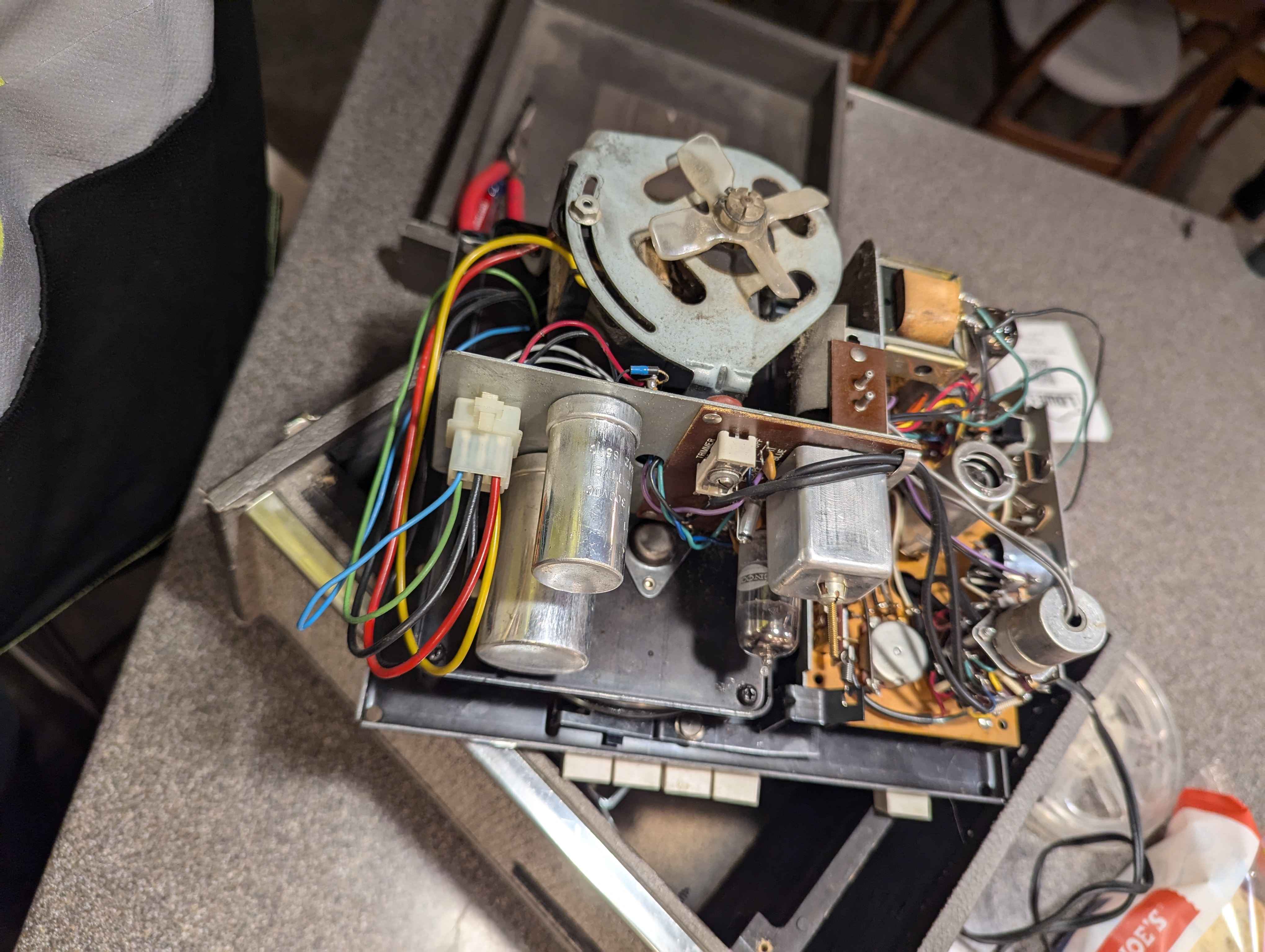 The underside of a reel to reel tape recorder. It is full of vacuum tubes, circuit boards, and a small electric motor.